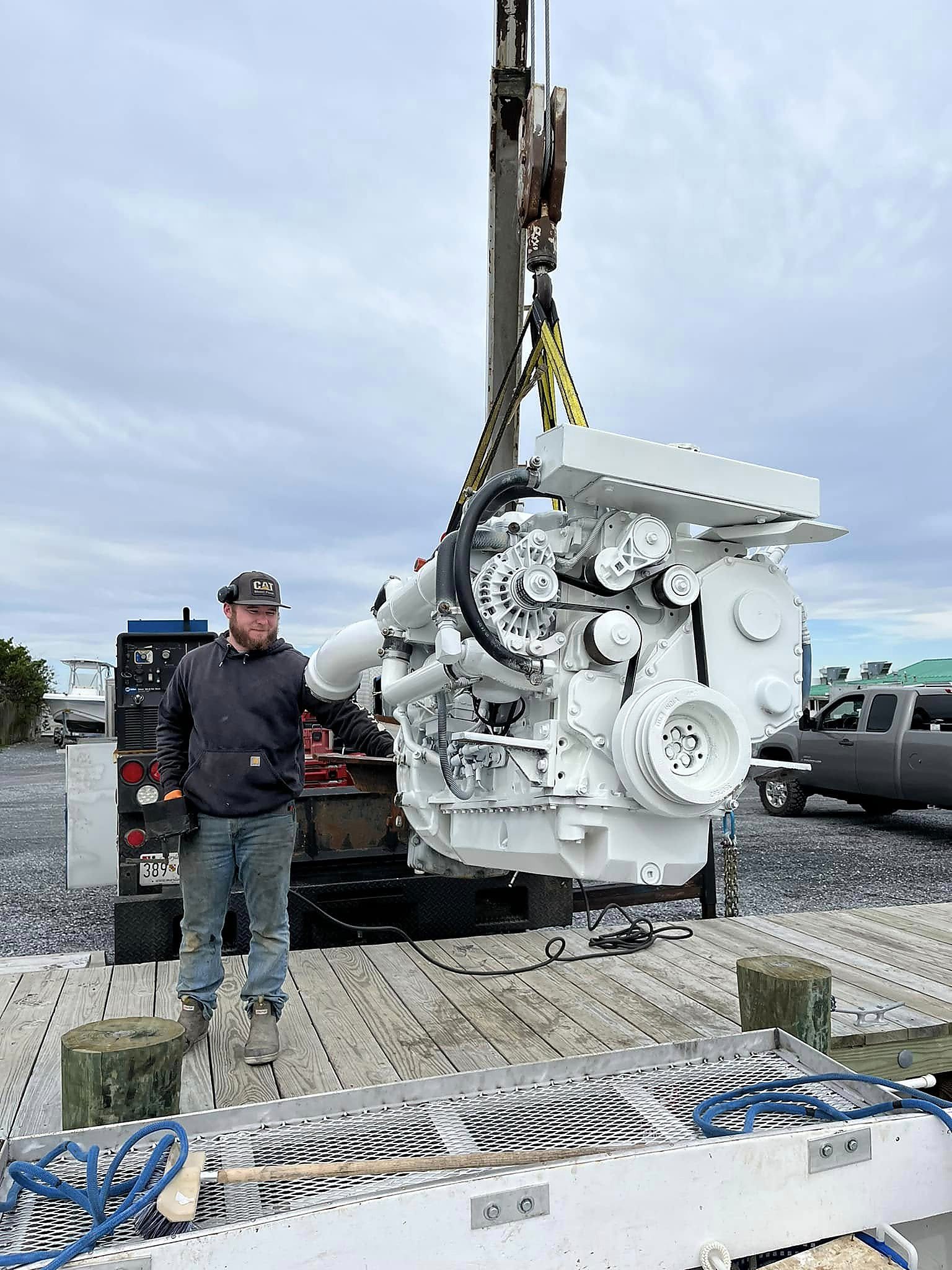 A marine diesel engine hanging from the crane on the dock, ready to go in